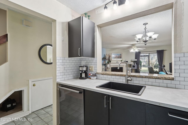 kitchen with pendant lighting, dishwasher, sink, decorative backsplash, and a textured ceiling