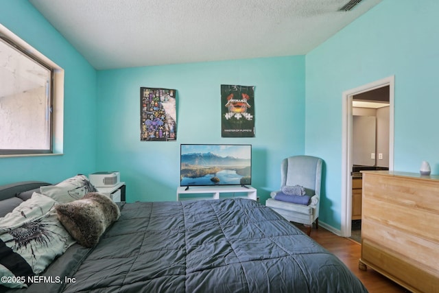 bedroom featuring wood-type flooring, vaulted ceiling, and a textured ceiling