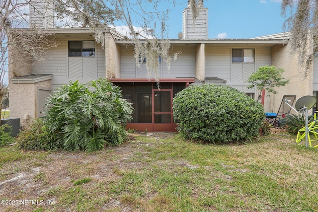 rear view of house with central AC, a sunroom, and a lawn