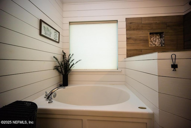 bathroom featuring a bath and wood walls