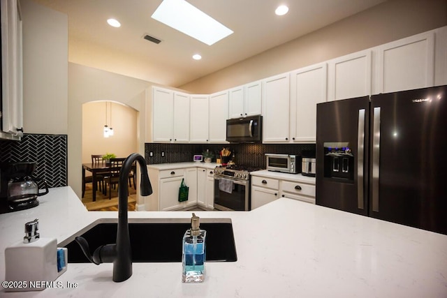 kitchen featuring white cabinetry, refrigerator with ice dispenser, gas range, and decorative backsplash