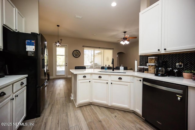 kitchen with pendant lighting, tasteful backsplash, white cabinetry, black appliances, and kitchen peninsula