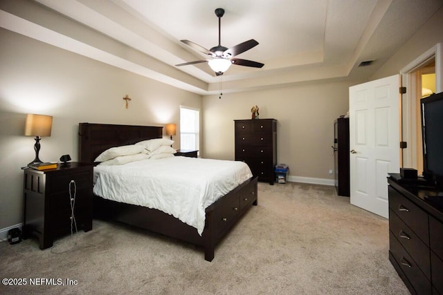 bedroom featuring a raised ceiling, light carpet, and ceiling fan