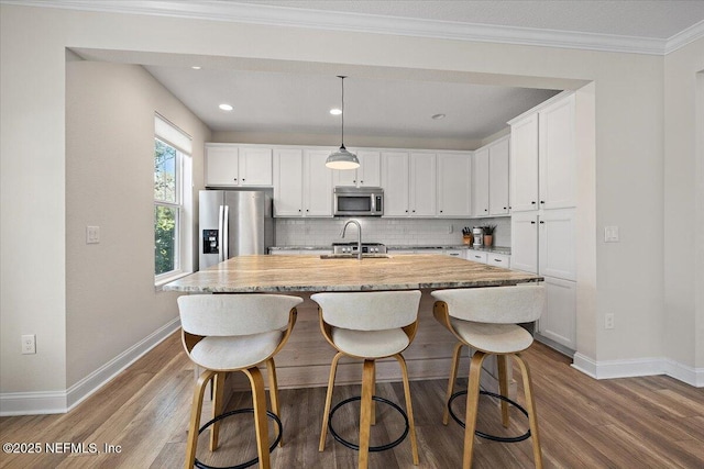 kitchen with a kitchen island with sink, white cabinetry, decorative backsplash, and appliances with stainless steel finishes