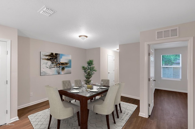 dining area featuring dark wood-type flooring and a textured ceiling