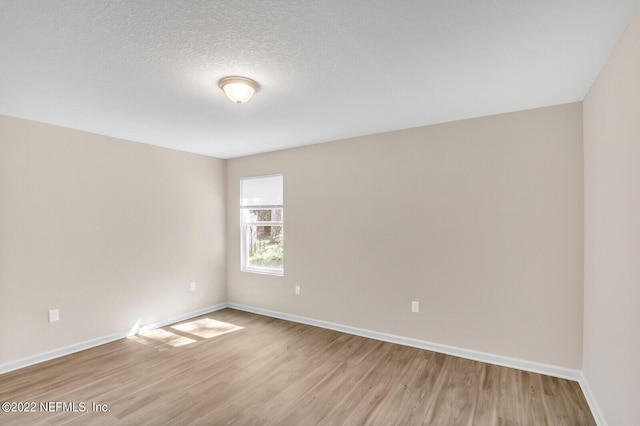 unfurnished room with light hardwood / wood-style floors and a textured ceiling