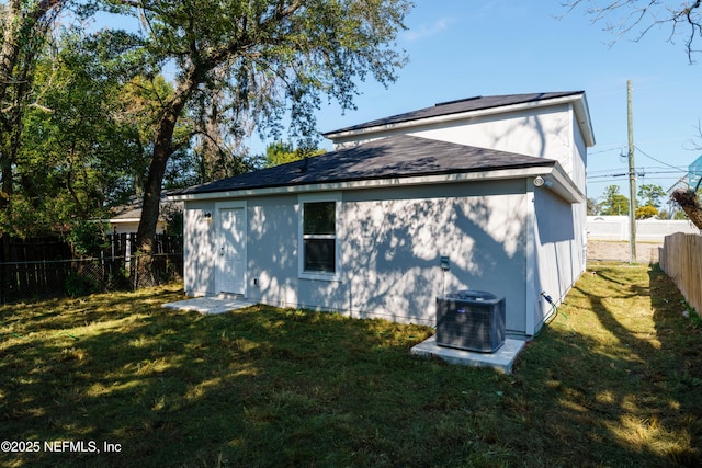 rear view of house with cooling unit and a yard