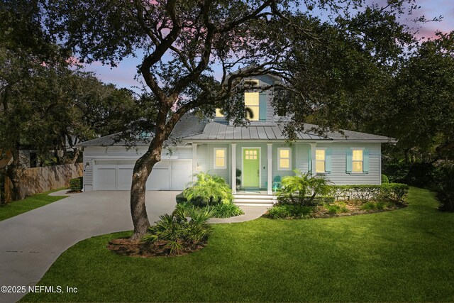 view of front of home featuring metal roof, an attached garage, fence, concrete driveway, and a front yard