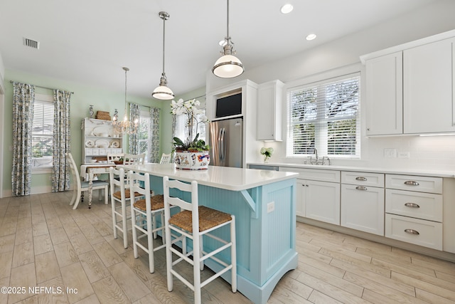 kitchen featuring light wood-style floors, white cabinetry, visible vents, and freestanding refrigerator