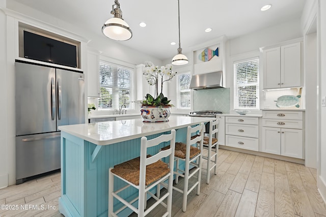 kitchen featuring light wood-style flooring, range hood, light countertops, and freestanding refrigerator