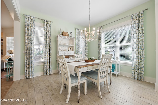 dining room with a healthy amount of sunlight, baseboards, a chandelier, and wood finished floors