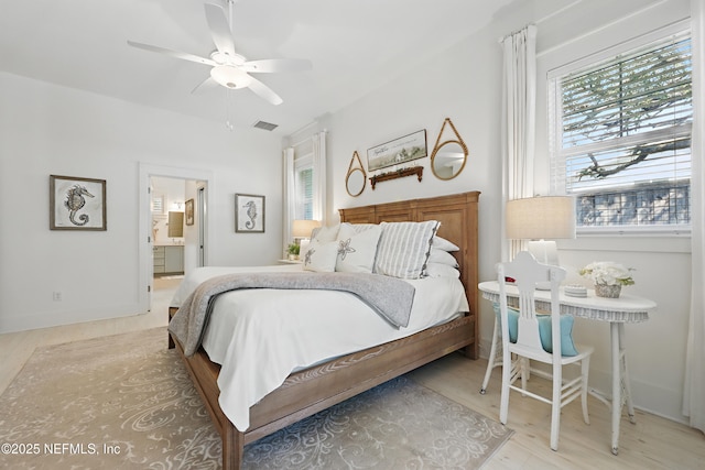 bedroom with ensuite bathroom, ceiling fan, wood finished floors, visible vents, and baseboards