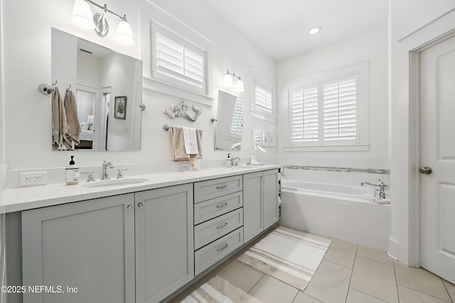 ensuite bathroom with double vanity, ensuite bathroom, a sink, tile patterned flooring, and a bath