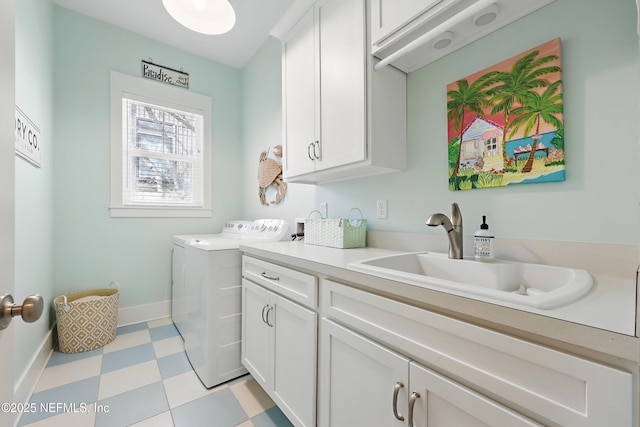 washroom with cabinet space, baseboards, washer and dryer, light floors, and a sink