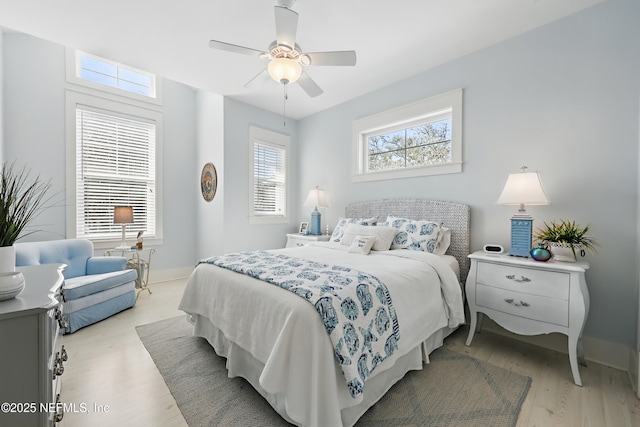 bedroom with light wood-style flooring, baseboards, and a ceiling fan