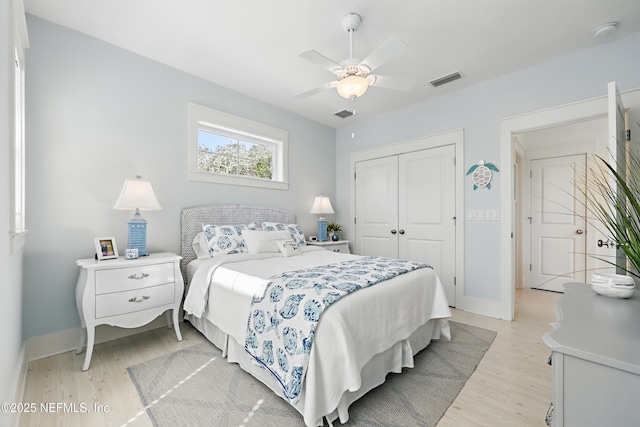 bedroom with light wood-type flooring, baseboards, visible vents, and a closet