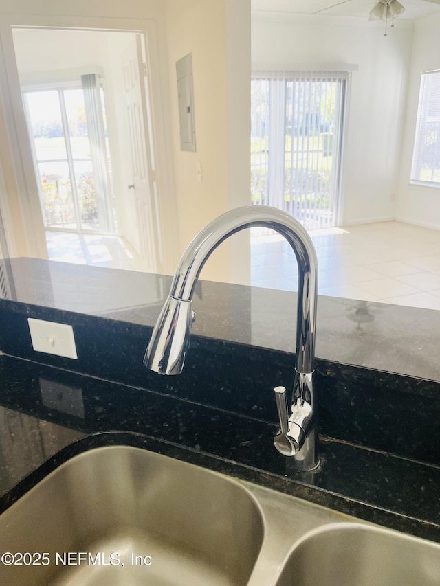 interior details featuring sink, electric panel, and dark stone counters