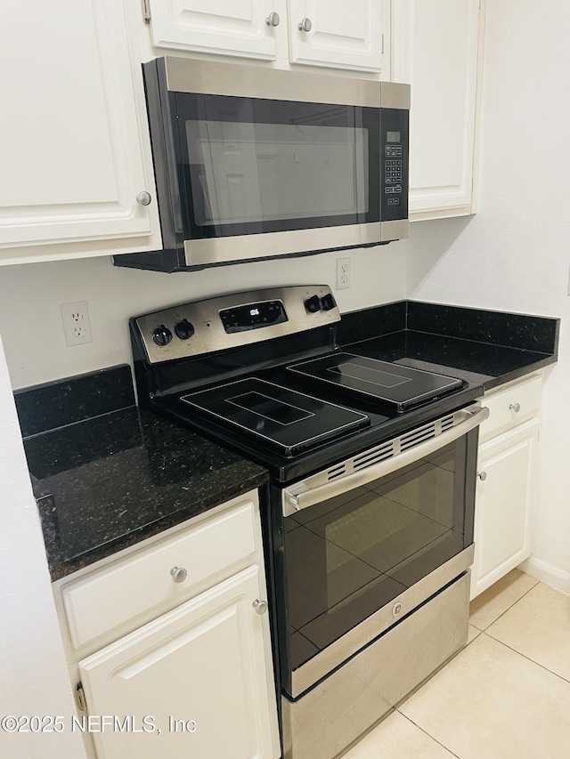 kitchen with stainless steel appliances, white cabinetry, and light tile patterned flooring