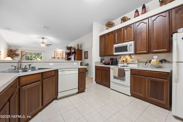 kitchen with sink, white appliances, light tile patterned floors, ceiling fan, and a textured ceiling