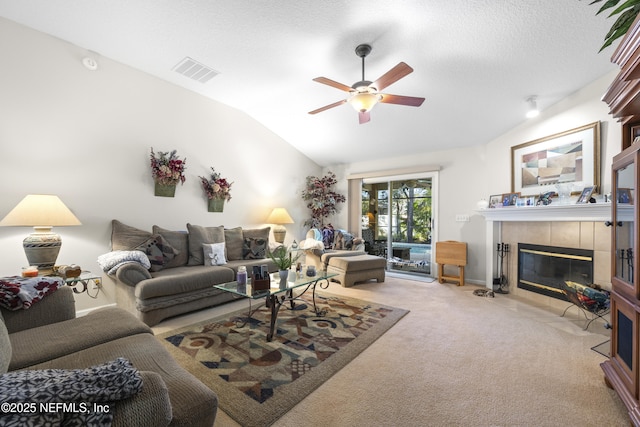 living room featuring light colored carpet, vaulted ceiling, a textured ceiling, ceiling fan, and a fireplace