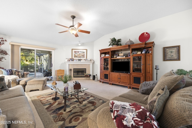 carpeted living room featuring ceiling fan, a fireplace, and vaulted ceiling