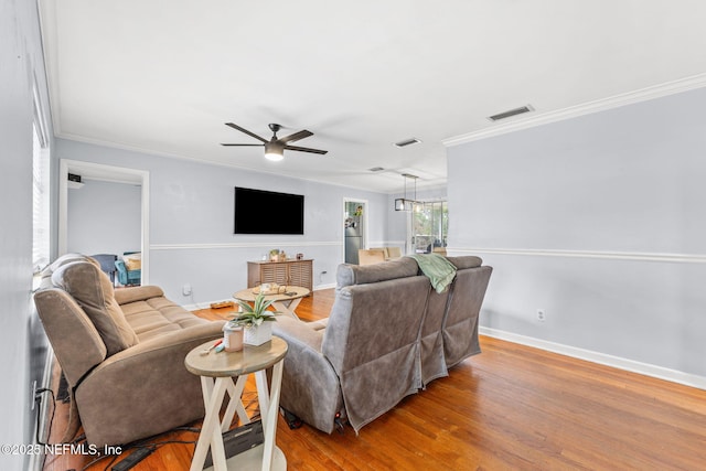 living room with hardwood / wood-style floors, crown molding, and ceiling fan