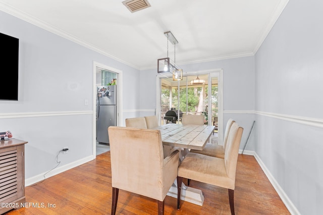 dining space featuring ornamental molding and light hardwood / wood-style flooring