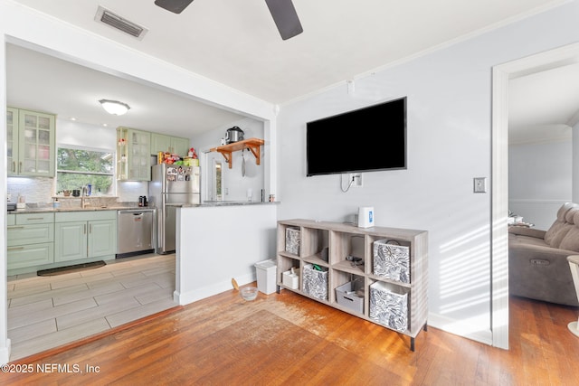 living room featuring crown molding, sink, ceiling fan, and light hardwood / wood-style flooring