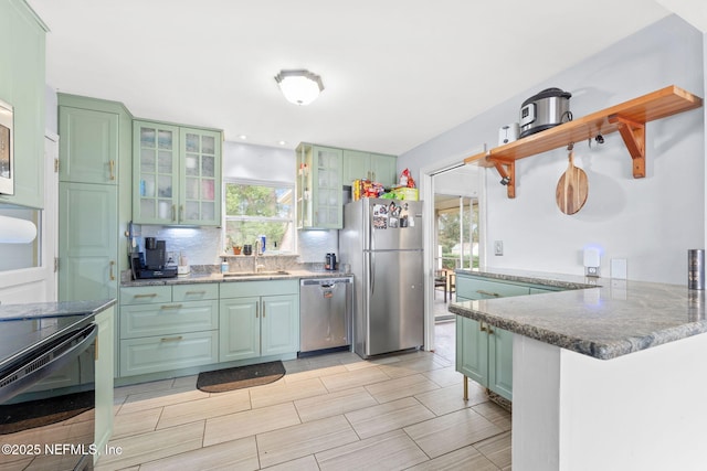 kitchen featuring sink, green cabinetry, kitchen peninsula, stainless steel appliances, and decorative backsplash