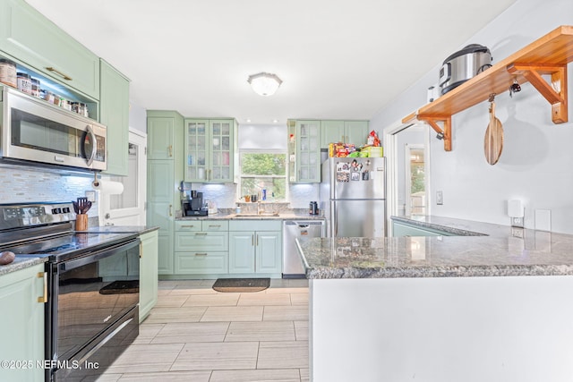 kitchen with sink, green cabinetry, kitchen peninsula, stainless steel appliances, and decorative backsplash