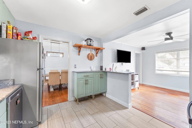 kitchen featuring stainless steel refrigerator, ceiling fan, kitchen peninsula, and green cabinets