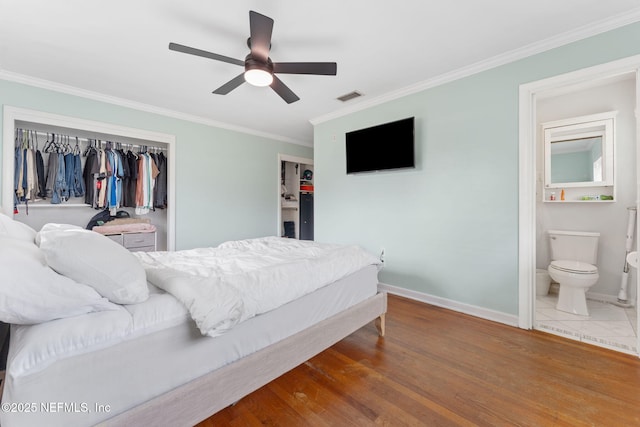 bedroom featuring ceiling fan, ensuite bathroom, wood-type flooring, ornamental molding, and a closet