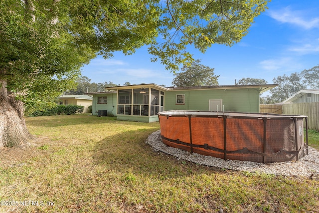 rear view of property with central AC unit, a lawn, and a sunroom