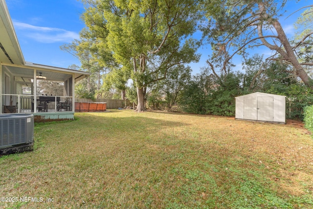 view of yard with a pool, a sunroom, cooling unit, and a storage unit