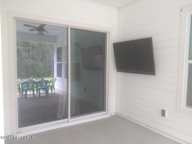 view of exterior entry with ceiling fan and a patio area