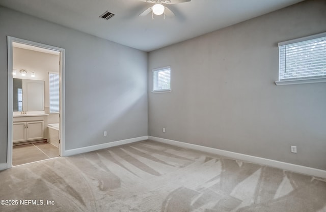 unfurnished bedroom featuring connected bathroom, light carpet, and ceiling fan