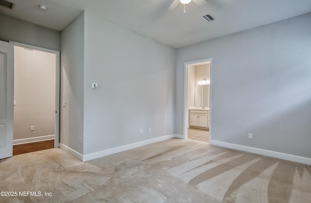 unfurnished bedroom featuring ceiling fan, light carpet, and ensuite bath