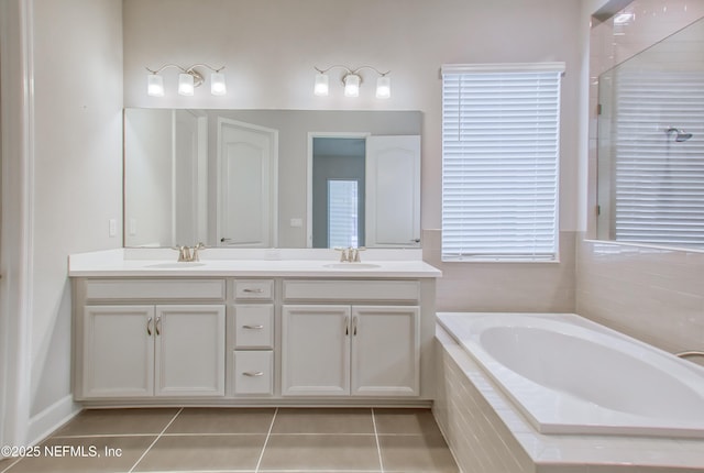 bathroom with tiled tub, vanity, and tile patterned floors