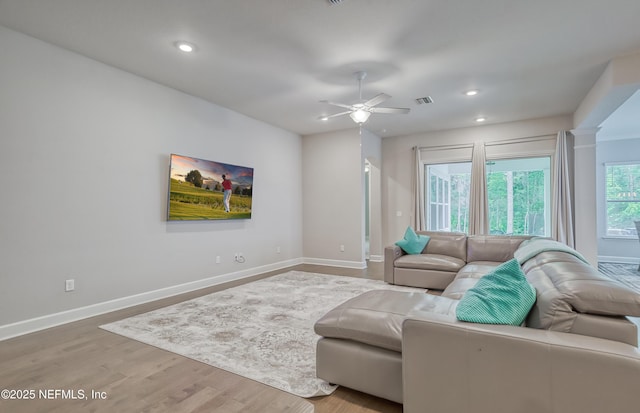 living room with hardwood / wood-style flooring, ceiling fan, and decorative columns