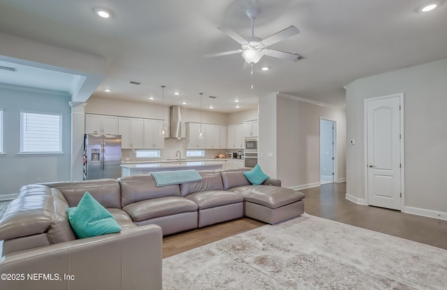 living room with crown molding, sink, ceiling fan, and light hardwood / wood-style floors