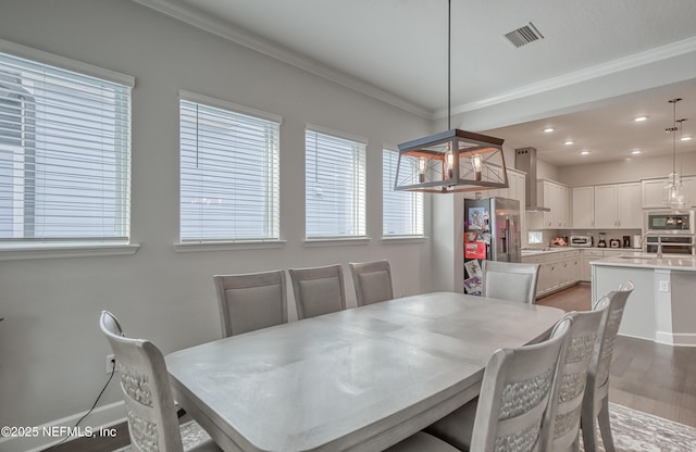 dining space featuring crown molding and light wood-type flooring