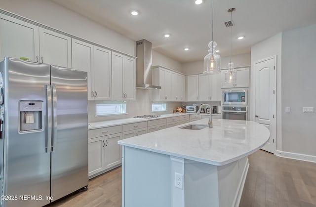 kitchen featuring a kitchen island with sink, pendant lighting, stainless steel appliances, and wall chimney exhaust hood