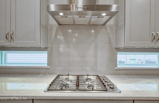 kitchen with extractor fan, light stone countertops, and stainless steel gas stovetop