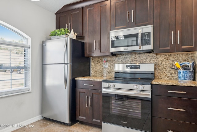 kitchen with tasteful backsplash, appliances with stainless steel finishes, light stone countertops, and light tile patterned floors