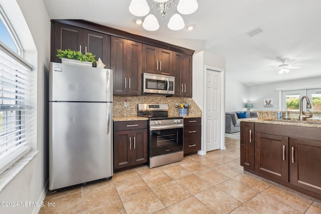 kitchen featuring dark brown cabinetry, sink, light stone counters, stainless steel appliances, and backsplash