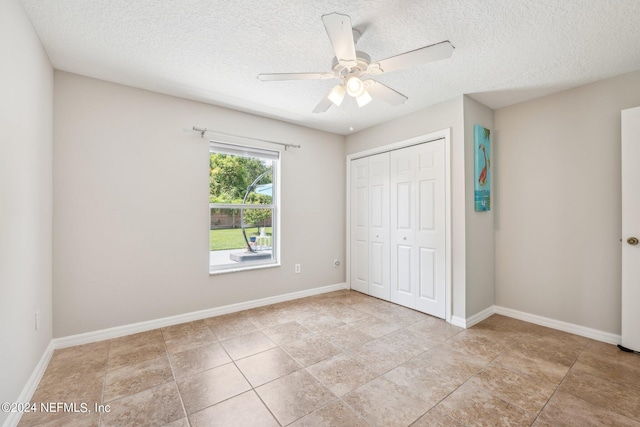 unfurnished bedroom featuring light tile patterned flooring, ceiling fan, a closet, and a textured ceiling