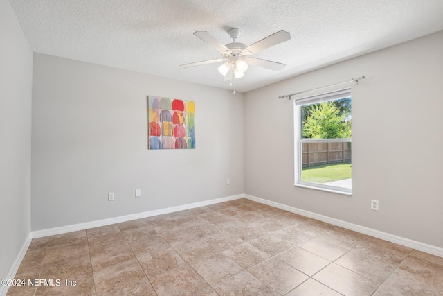 tiled empty room featuring ceiling fan and a textured ceiling