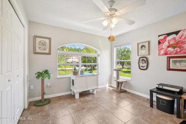 miscellaneous room featuring light tile patterned flooring, ceiling fan, a textured ceiling, and a wealth of natural light