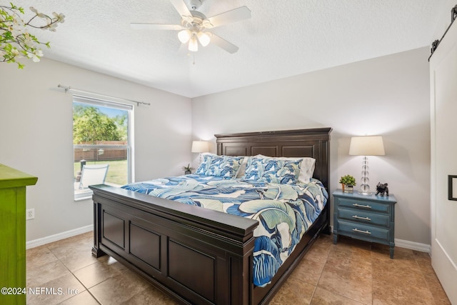 bedroom featuring ceiling fan, a textured ceiling, and light tile patterned floors