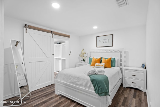 bedroom featuring dark hardwood / wood-style flooring and a barn door